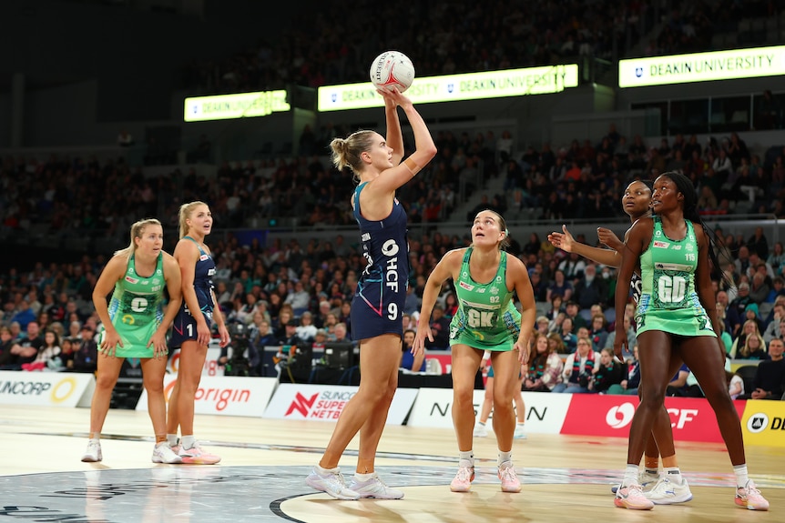 A Melbourne Vixens Super Netballer gets ready to shoot the ball as West Coast Fever defenders watch.