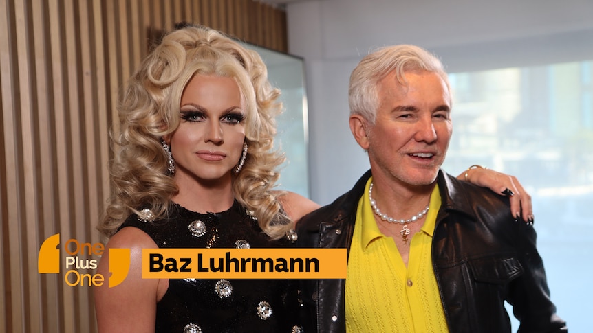 Glamourously dressed drag queen with blonde curly hair stands next to white-haired man with yellow shirt and leather jacket