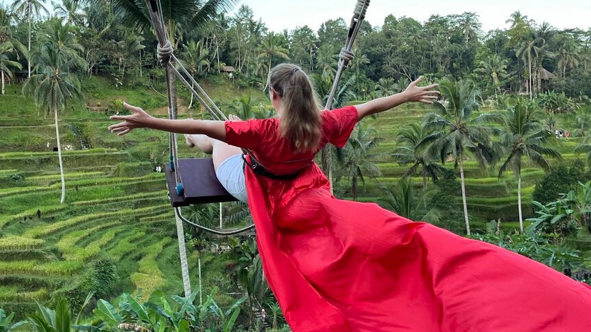 Woman on a swing with a billowing red dress 