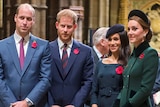 Prince William stands to the left, with Prince Harry to his right, followed by Meghan and Kate. The foursome sport poppies.