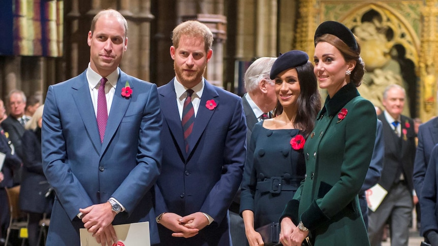 Prince William stands to the left, with Prince Harry to his right, followed by Meghan and Kate. The foursome sport poppies.