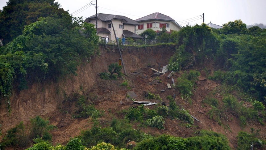 Rescue workers look at a landslide caused by heavy rains in Japan