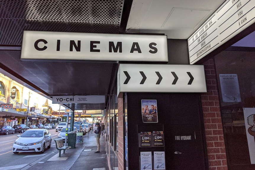 A white sign points to where a cinema is inside an arcade.