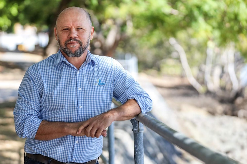 A man, Mike Foster, SEQ Water Communications Manager, leans against a railing next to the Brisbane River.