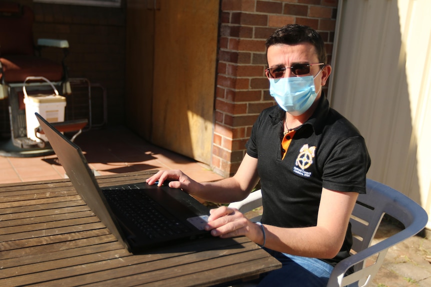 Former Qantas worker Theo Seremetidis types on a laptop computer in his yard