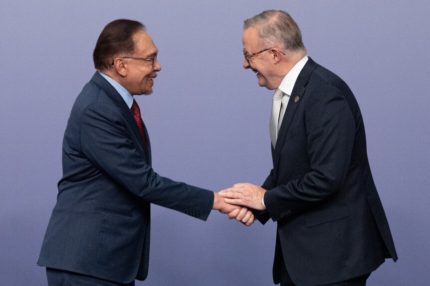 Anwar Ibrahim and Anthony Albanese shake hands, both are smiling