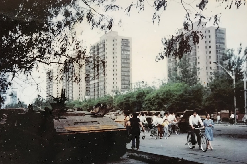 An aged photo of a tank and people walking the streets at Chongwenmen Avenue after the Tiananmen Square massacre in June 1989.