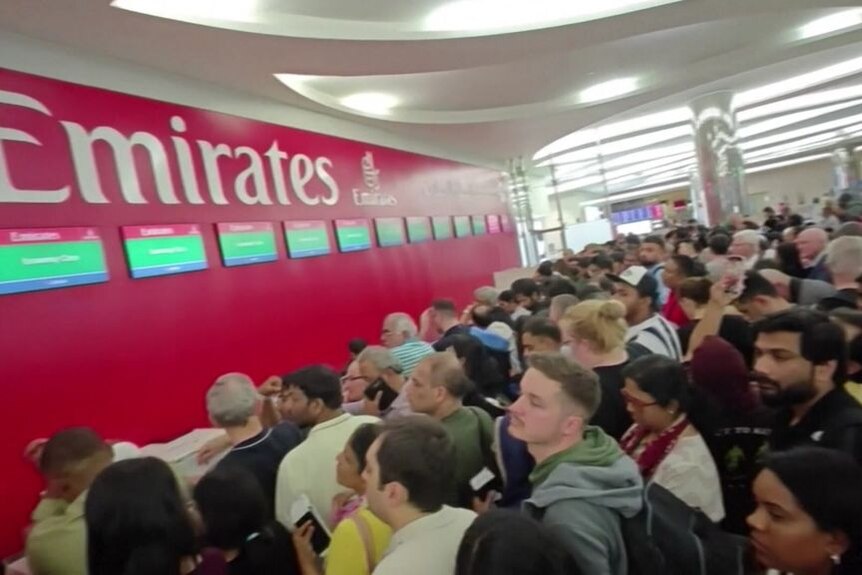 A crowd of people lined up at the Emirates service desk.