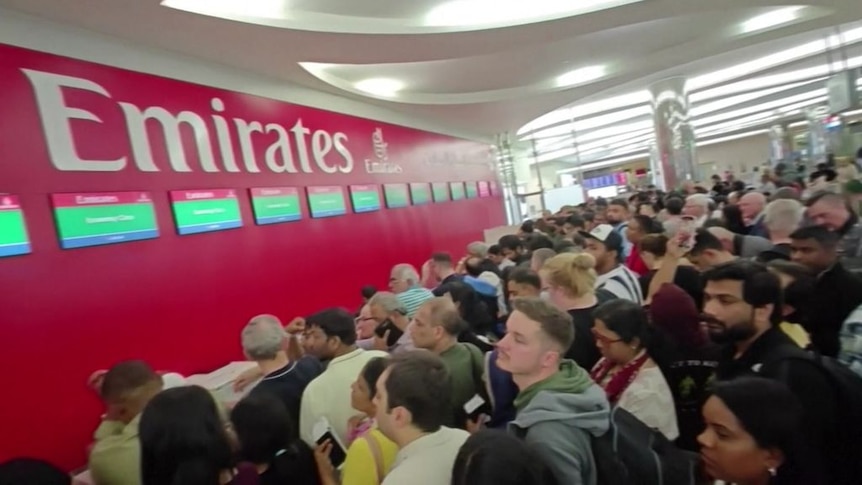 A crowd of people lined up at the Emirates service desk.