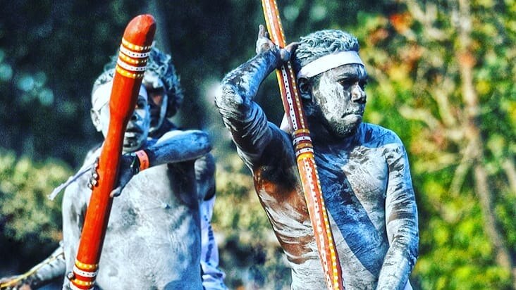 Two indigenous men dance in a traditional ceremony.