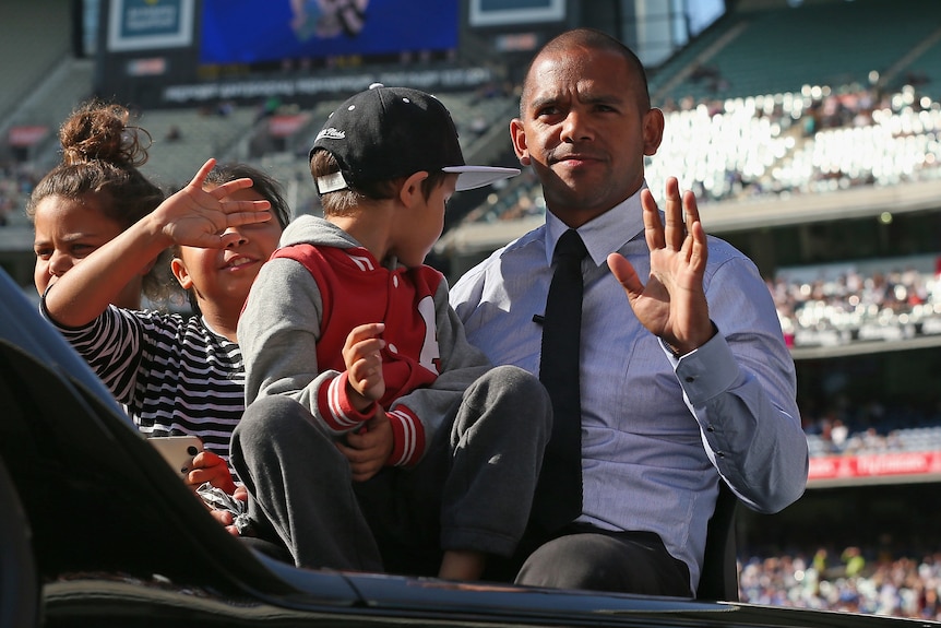 A man waves to the crowd during a lap of honour 