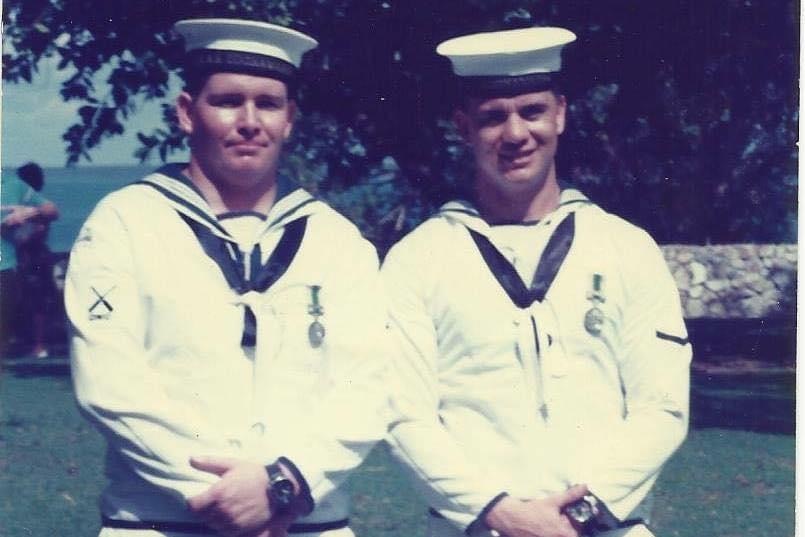 Two sailors stand side-by-side in their uniforms.