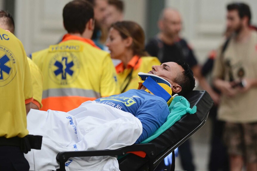 A man in a neck brace on a stretcher is taken away by paramedics.