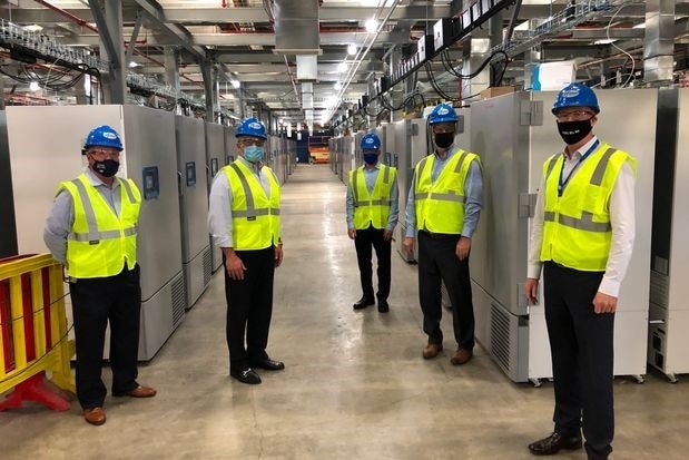 Men wearing hi-vis vests stand in front of industrial freezers.