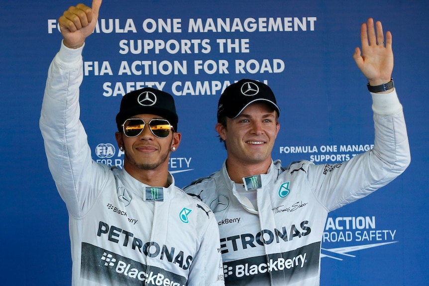 Two racing drivers wave to fans.