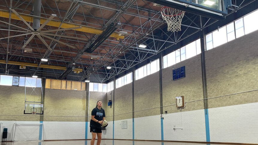 A woman prepares to shoot a basketball at a hoop.