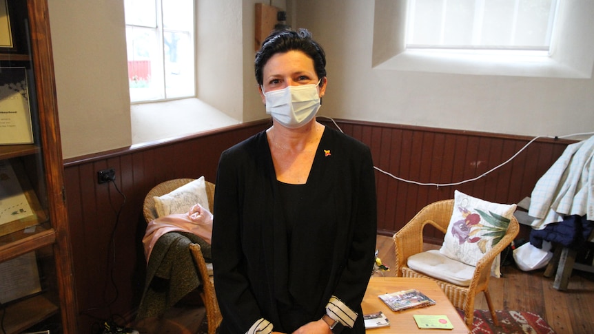 woman with short black hair standing with face mask