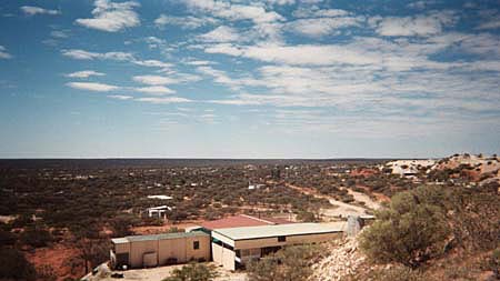 An older photo of buildings in the remote community of Mintabie among low lying scrublands.