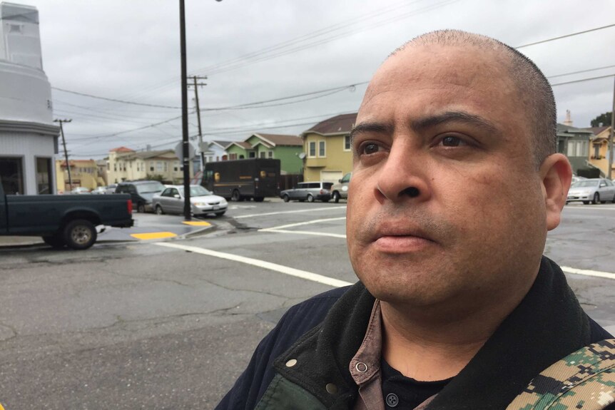 Joaquin Sotelo stands in the street outside a row of houses in America