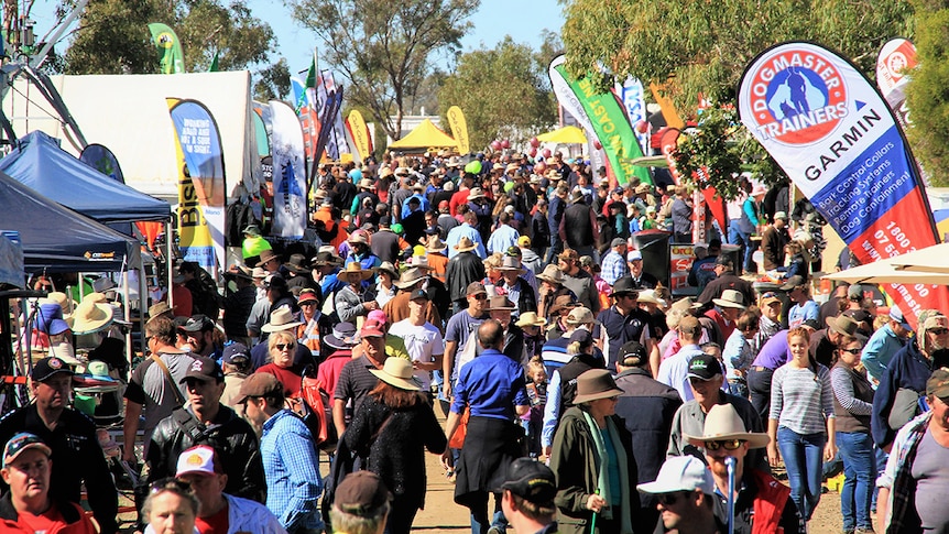 A crowd of people walking between stalls at the FarmFest agricultural field day.