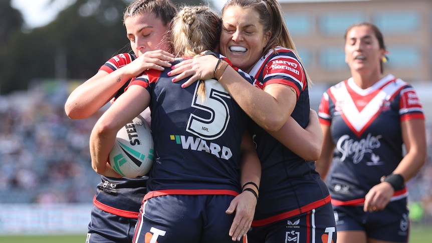 Roosters players smile and engage in a hug after a try