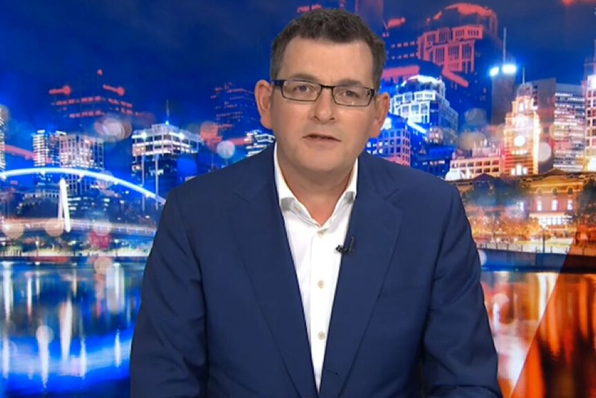 Victorian Premier Daniel Andrews wears a navy suit and glasses in front of a Melbourne backdrop on Q+A.