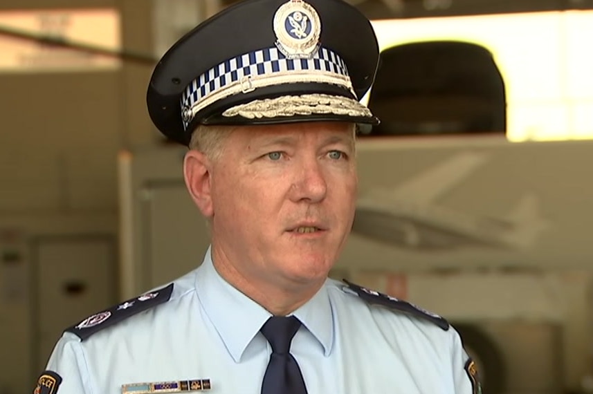 Commissioner Fuller is in his NSW Police uniform and hat, addressing the media, looking right of frame.