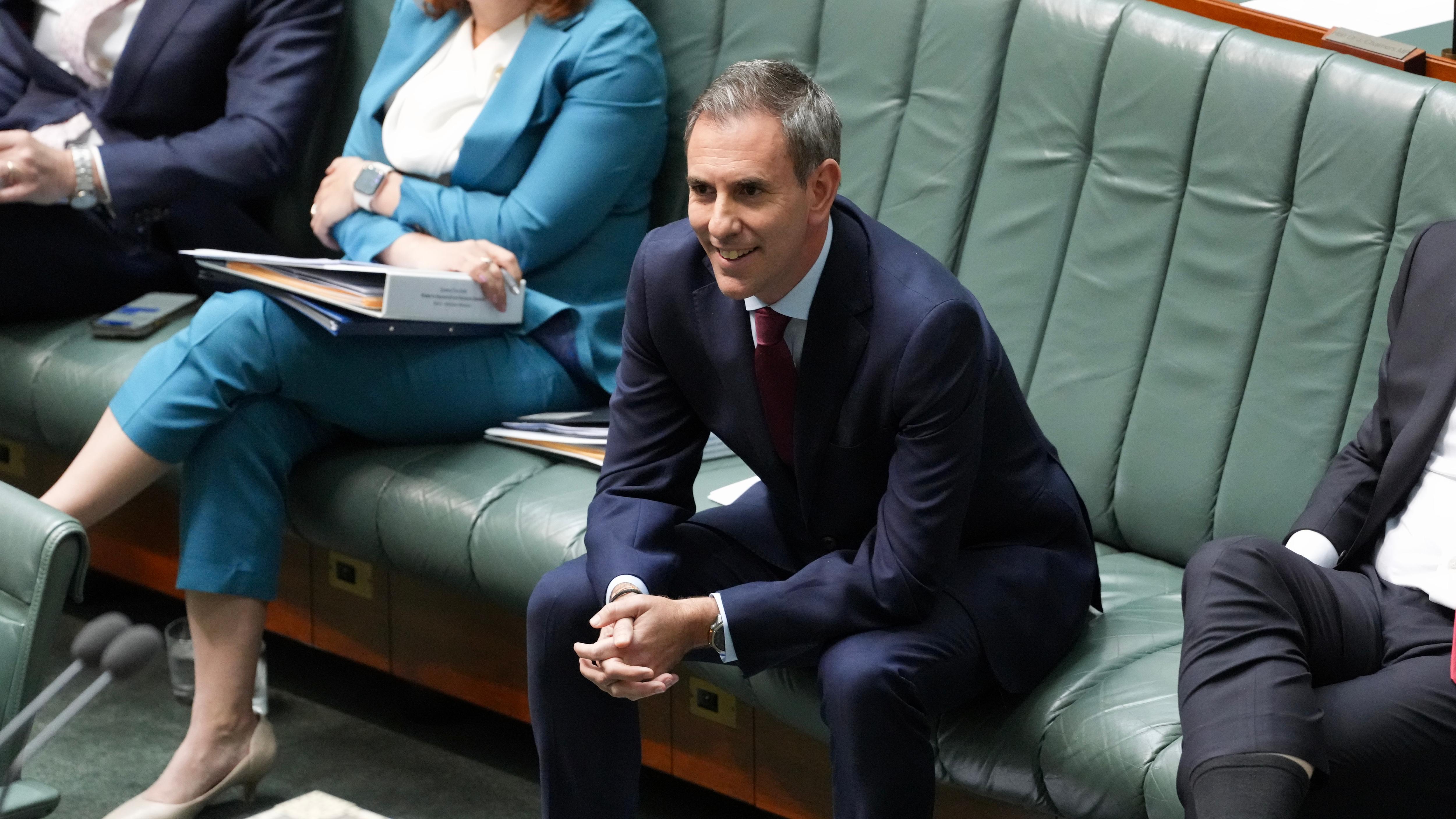 Jim Chalmers leans forward with his elbow on knees and hands clasped while sitting in the chamber.
