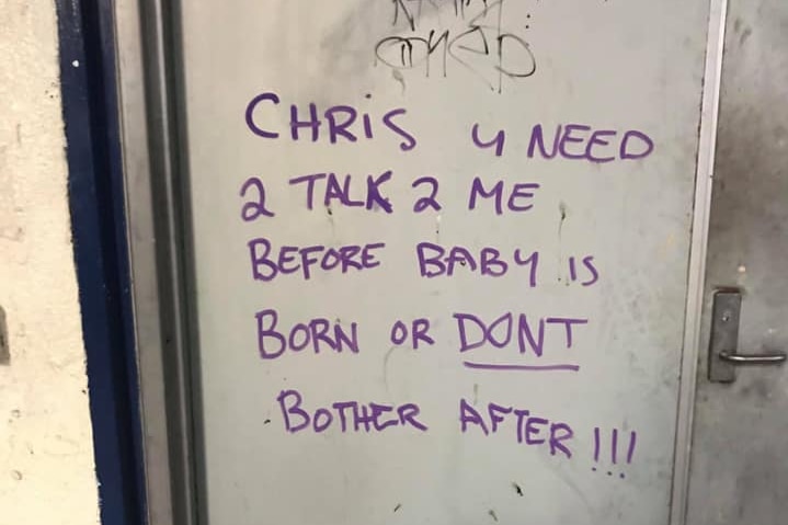 Graffiti on a silver door reads 'Chris u need 2 talk 2 me b4 baby is born or dont bother after'.