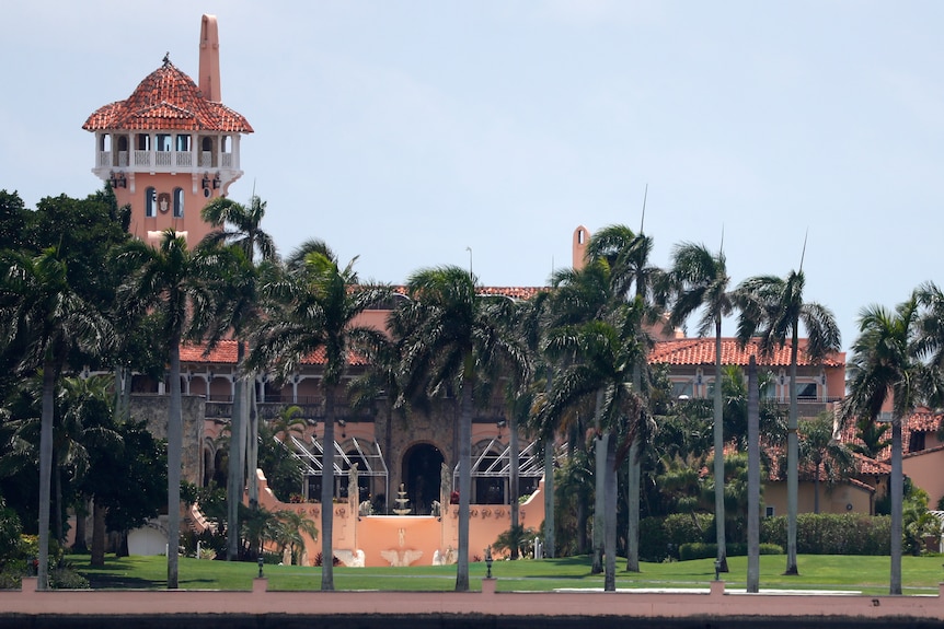 The Mar-a-Lago resort behind a row of palm trees.
