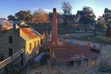 An aerial view of the goldfields museum Sovereign Hill at Ballarat showing a big chimney and old weatherboard buildings.
