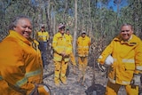 Group of women standing in bushland wearing yellow fire jackets and pants.