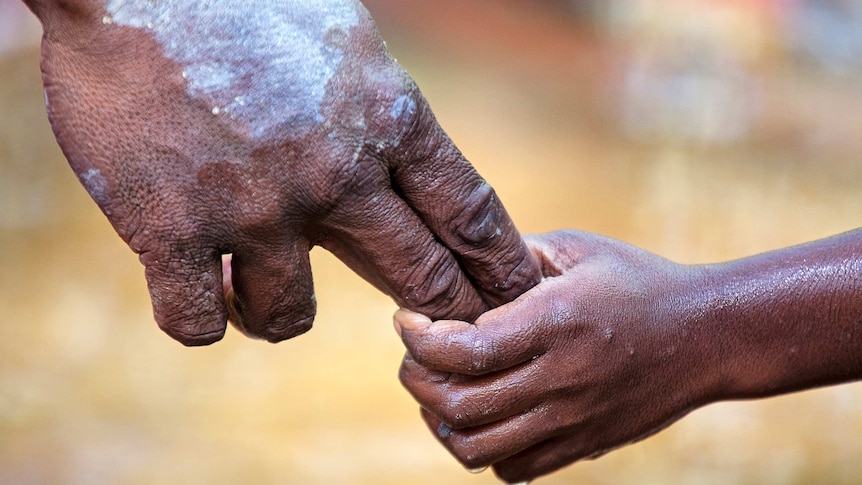 Close up image of Aboriginal father and son holding hands.