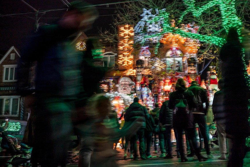a group of people stand outside a display of lights and decorations at a house in Brooklyn, New York