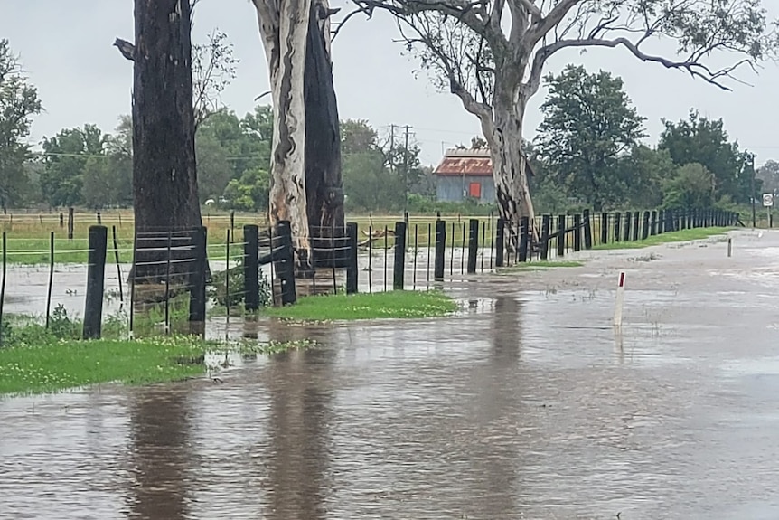 A flooded road next to a farm.
