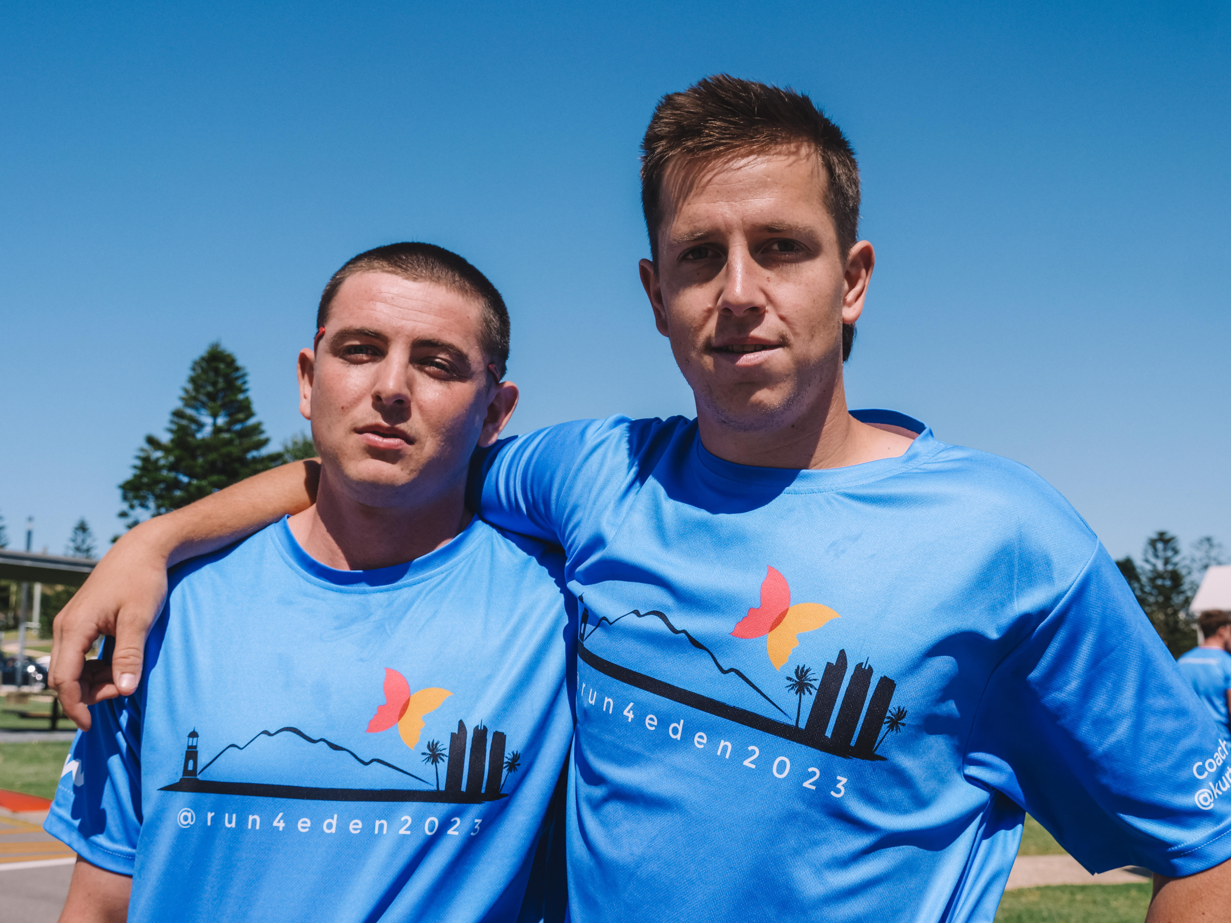 two friends standing together, one has his arm around the other