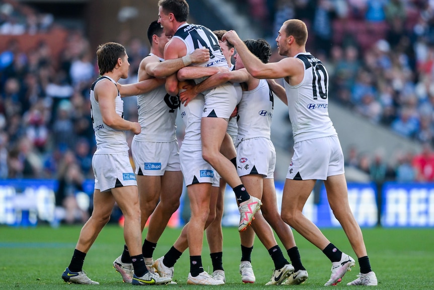 Carlton players celebrate in a big huddle