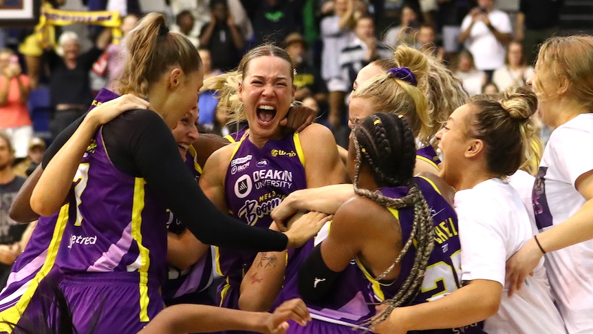 Melbourne Boomers players jump and smile in a huddle