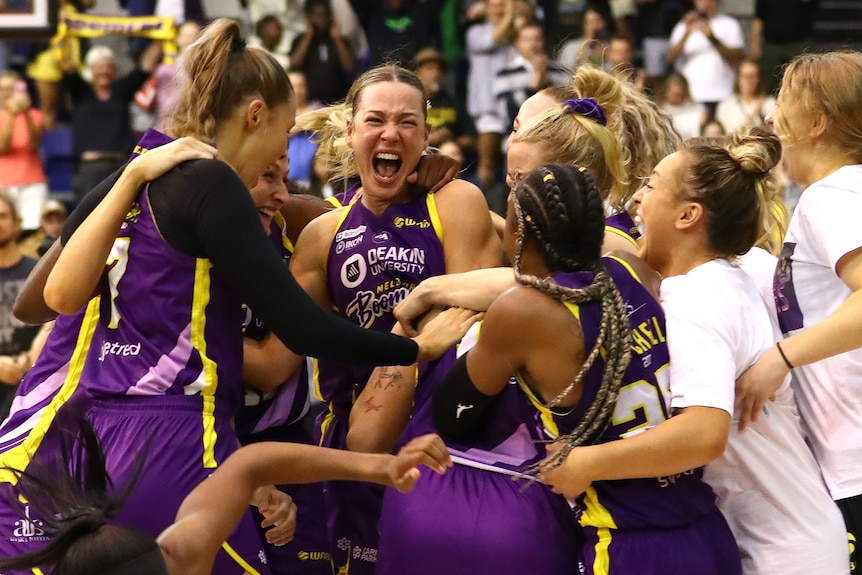 Melbourne Boomers players jump and smile in a huddle