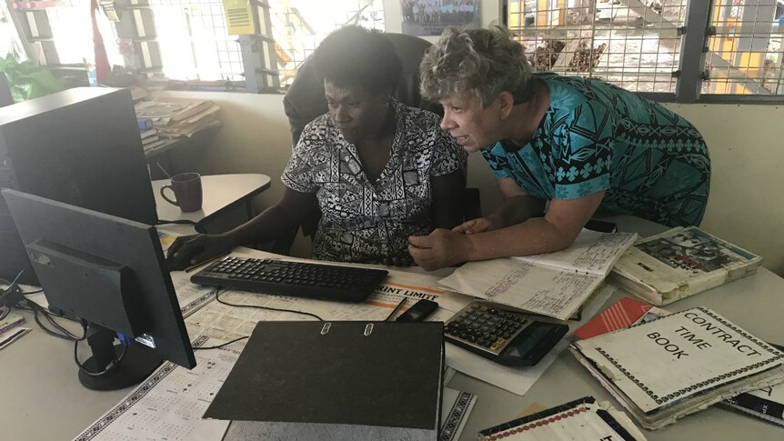 Liane Arno and a worker look at a computer.