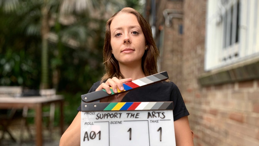 A young woman holding a clapper board