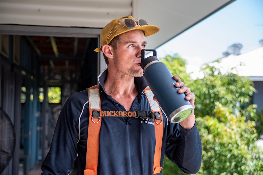 A carpenter drinks water on a construction site. 