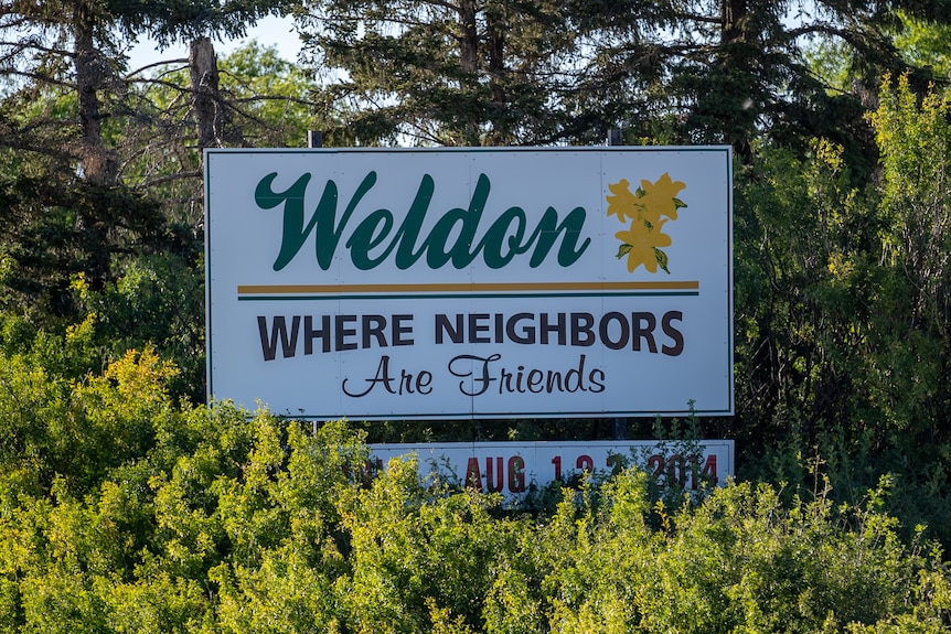 A sign surrounded by trees, which reads: "Weldon: Where Neighbors Are Friends" 