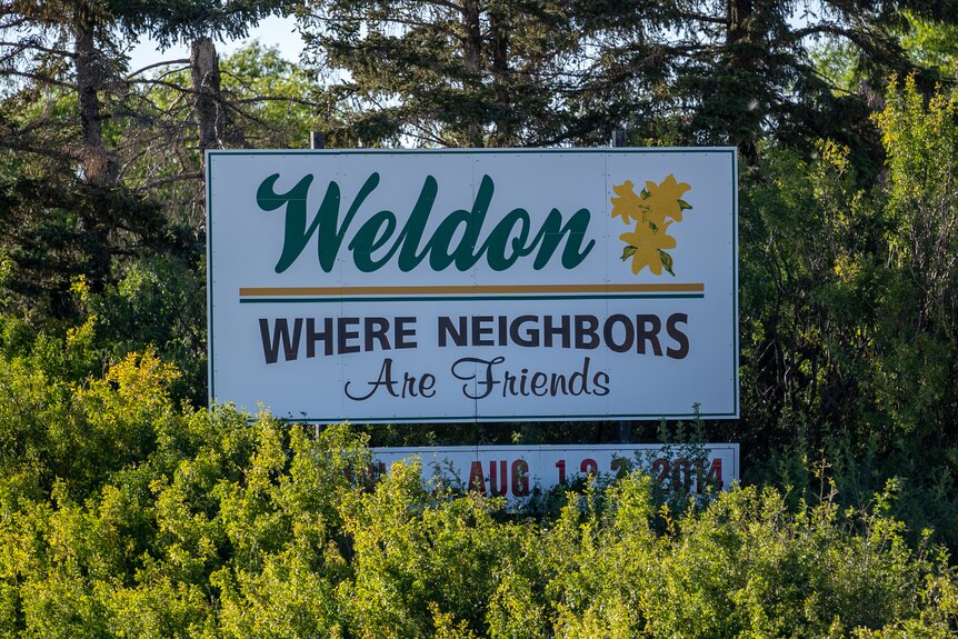 A sign surrounded by trees, which reads: "Weldon: Where Neighbors Are Friends" 