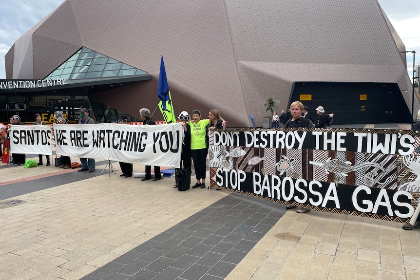 Protesters hold banners outside an Annual General Meeting.