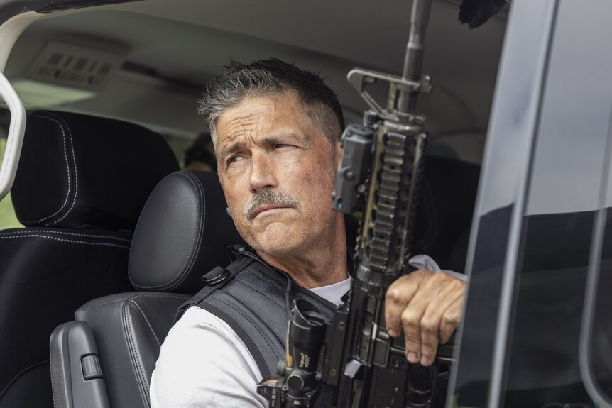 Matthew Fox as Lt Pete holding a gun while sitting in a vehicle with a serious expression on his face
