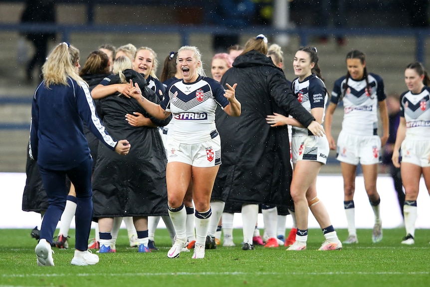 England players smile and hug after beating Brazil at the Women's Rugby League World Cup.