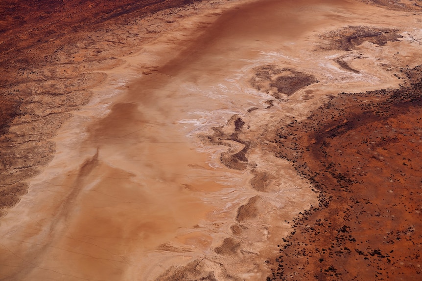 Red, brown and white salt plains on the Central Australian landscape are seen from the air