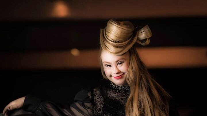 Model Madeline Stuart smiles in a fashion shoot where her hair has been swept up like a hat.