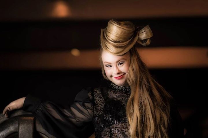 Model Madeline Stuart smiles in a fashion shoot where her hair has been swept up like a hat.